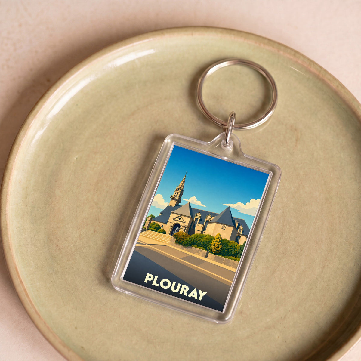 Porte-clés souvenir de la ville de Plouray avec une illustration stylisée de son église.