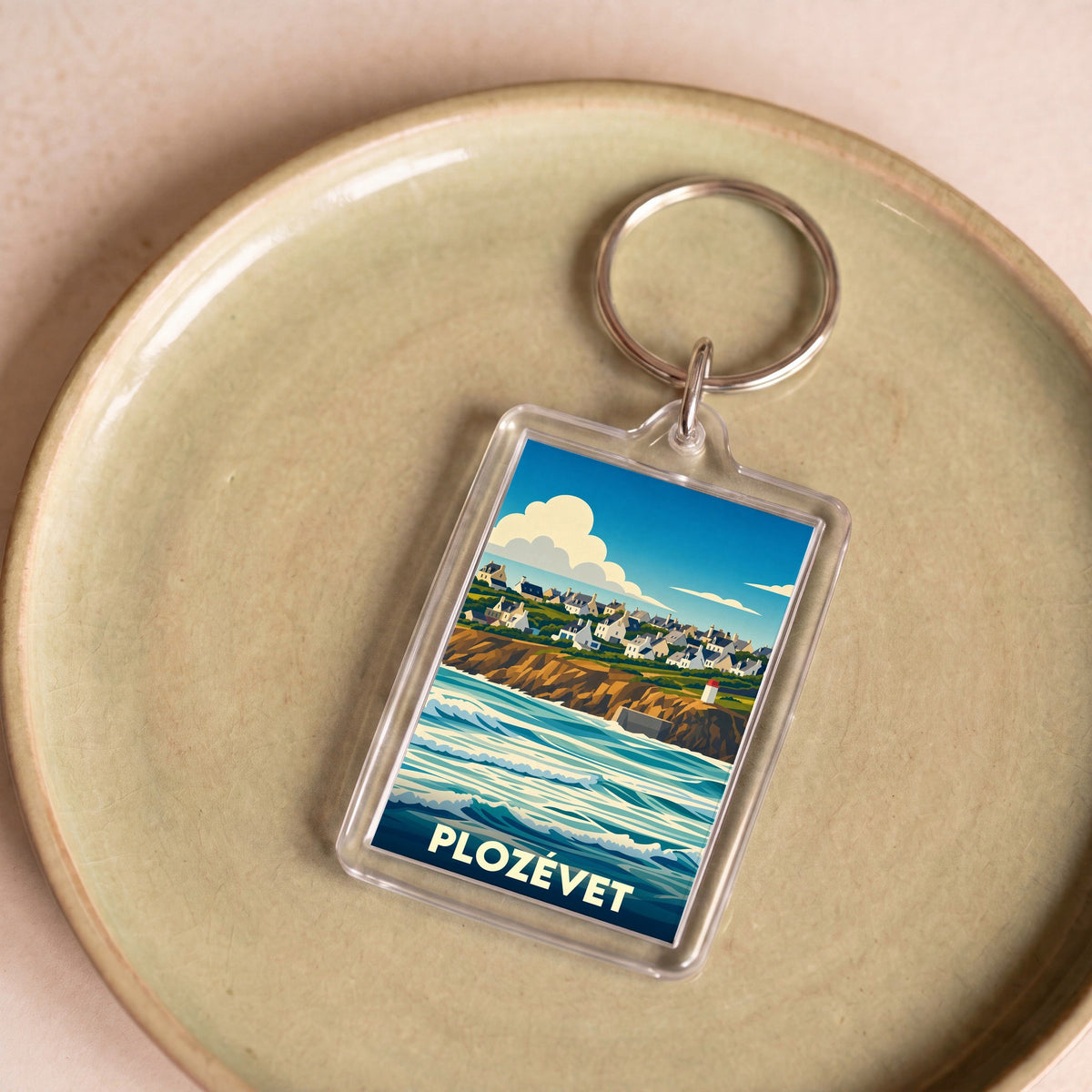 Porte-clés souvenir de la ville de Plozévet avec une illustration stylisée du littoral et de ses maisons.