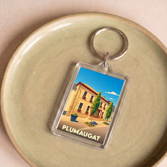 Porte-clés souvenir de la ville de Plumaugat avec une illustration stylisée d'un bâtiment fleuri.