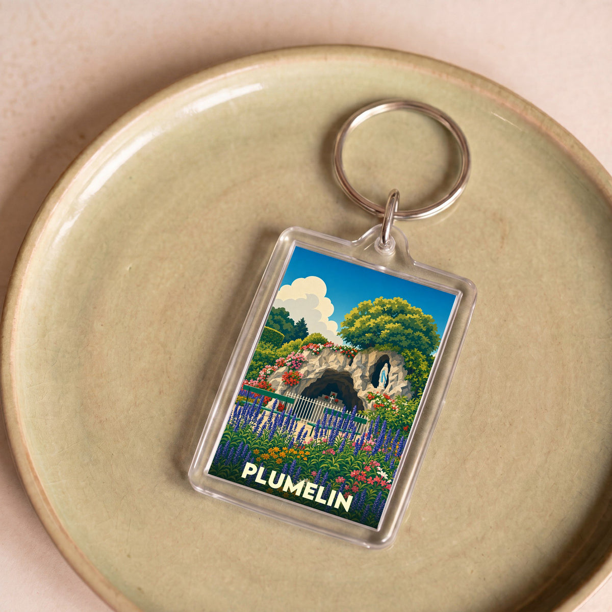 Porte-clés souvenir de la ville de Plumelin avec une illustration stylisée d'une grotte fleurie.
