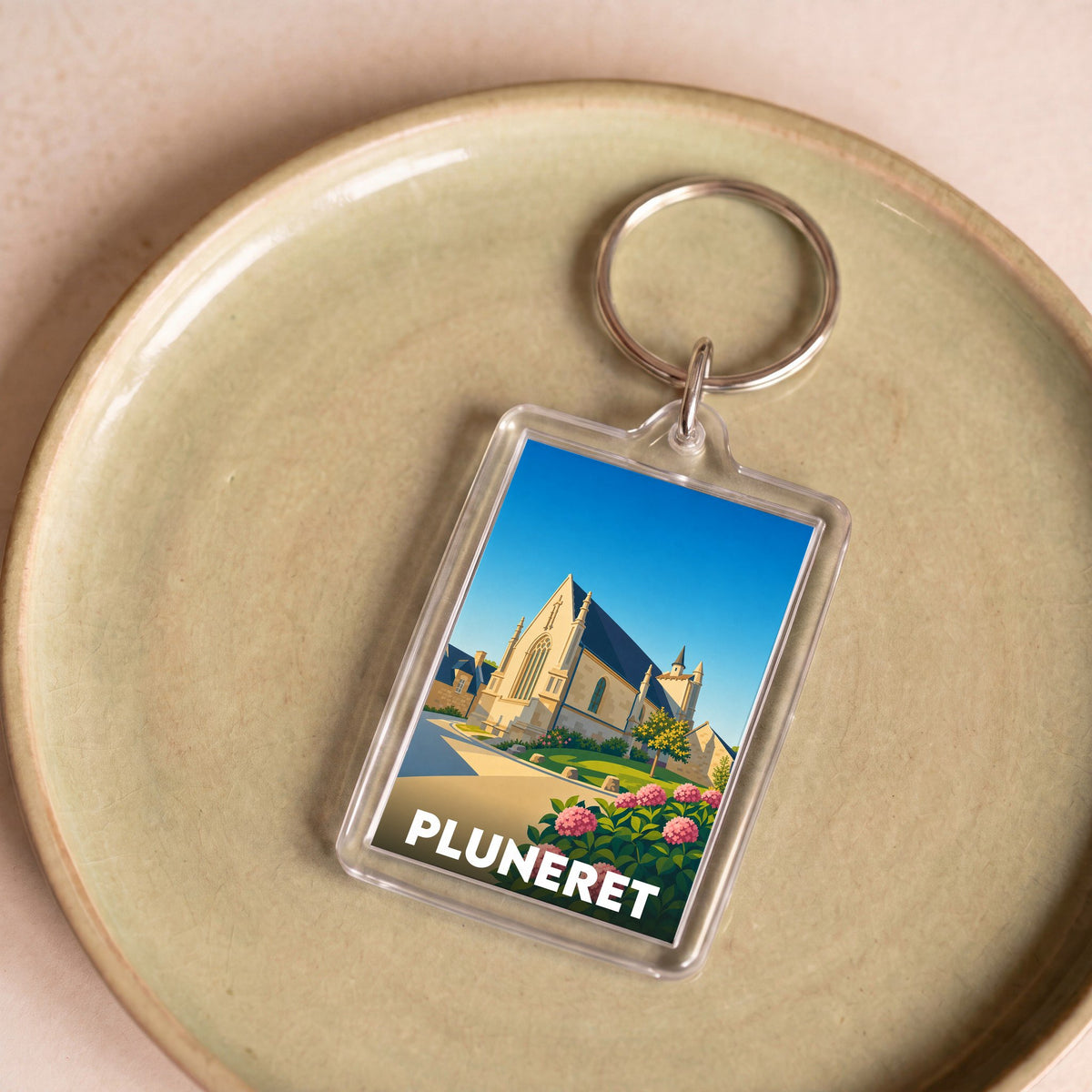 Porte-clés souvenir de la ville de Pluneret avec une illustration stylisée de son église.