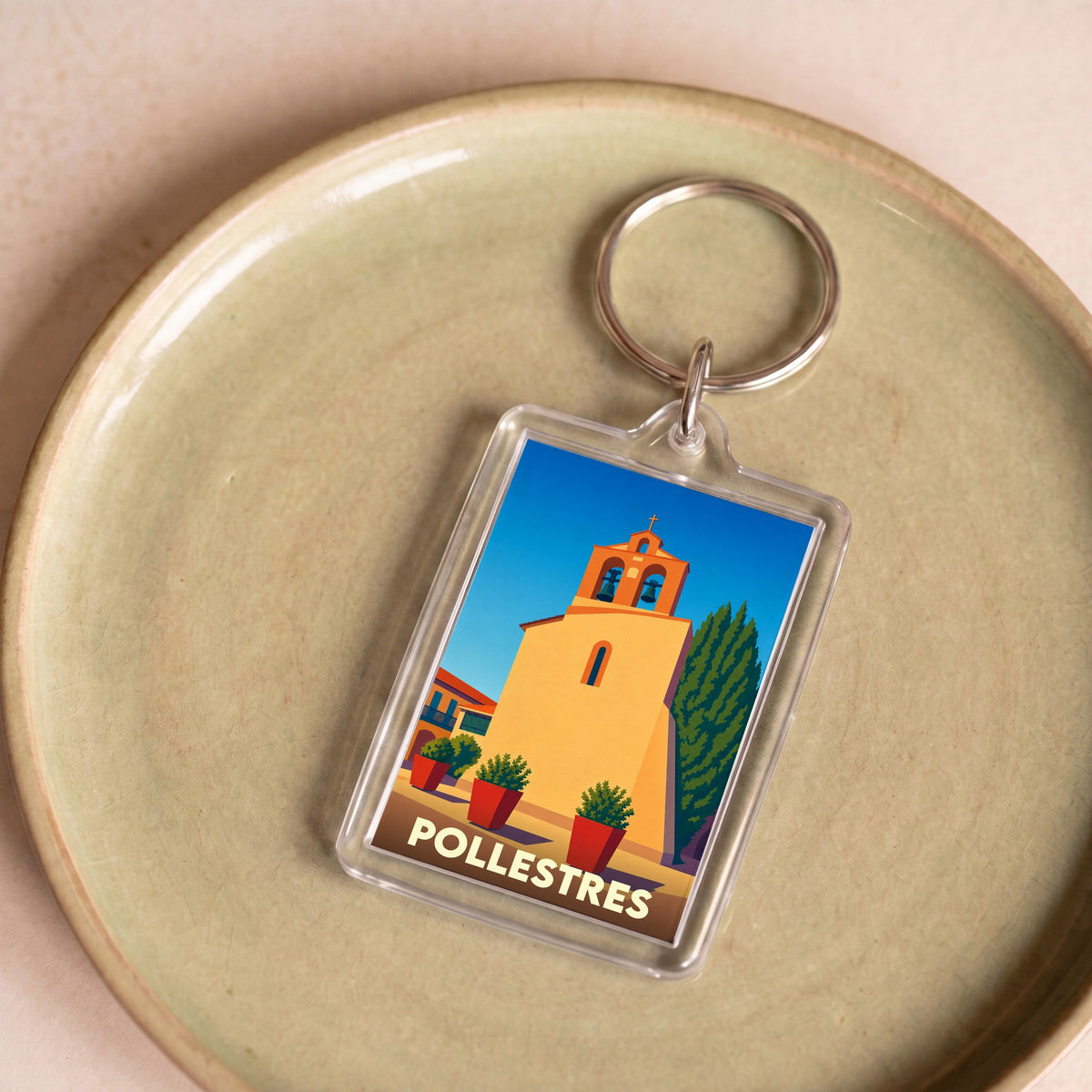 Porte-clés souvenir de la ville de Pollestres avec une illustration stylisée de son église.