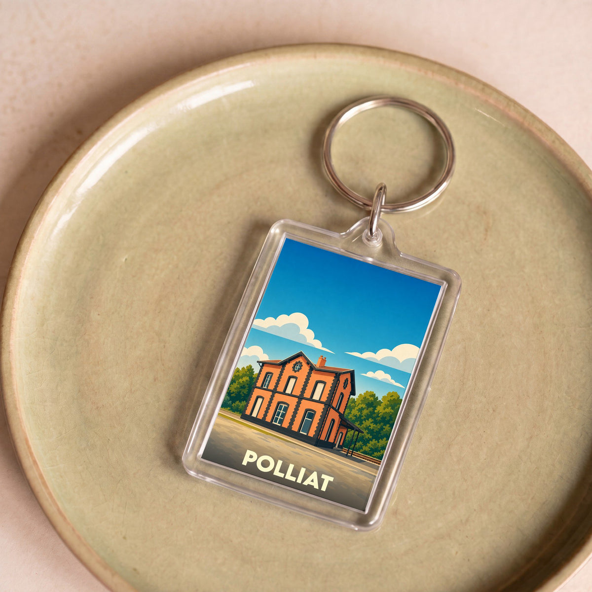 Porte-clés souvenir de la ville de Polliat avec une illustration stylisée de son ancienne gare.