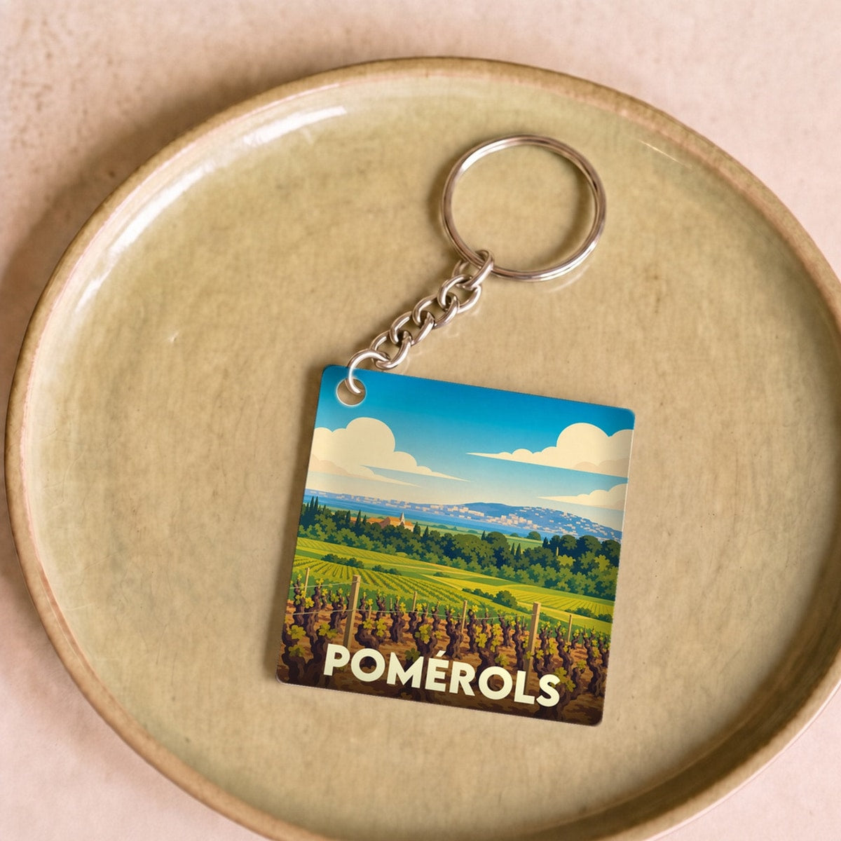 Porte-clés souvenir de la ville de Pomérols avec une illustration stylisée de vignobles.