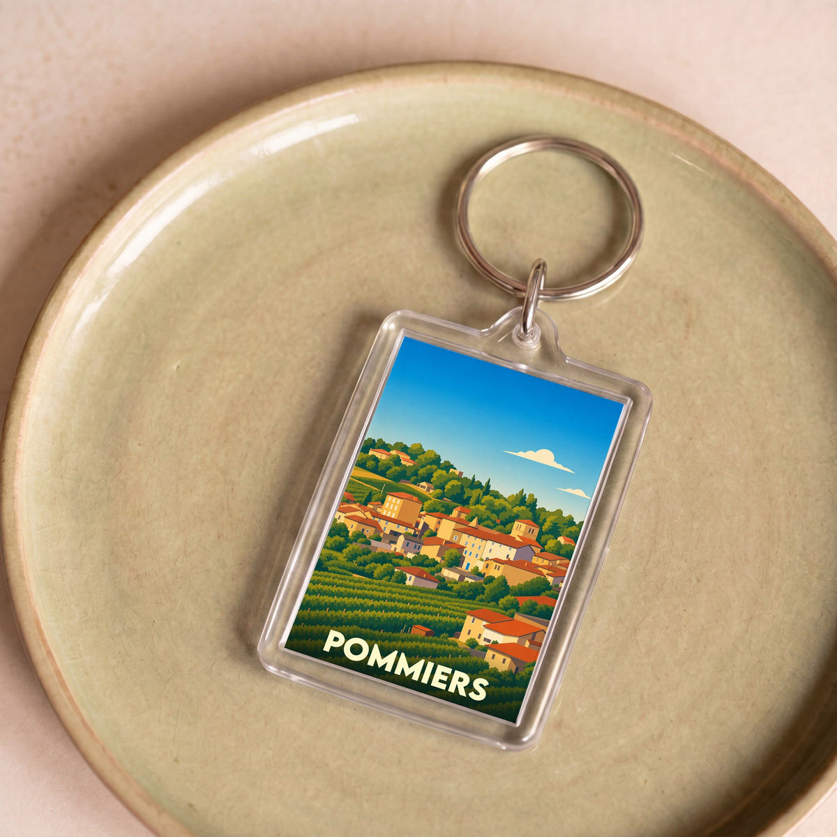 Porte-clés souvenir de la ville de Pommiers avec une illustration stylisée de son paysage vallonné.