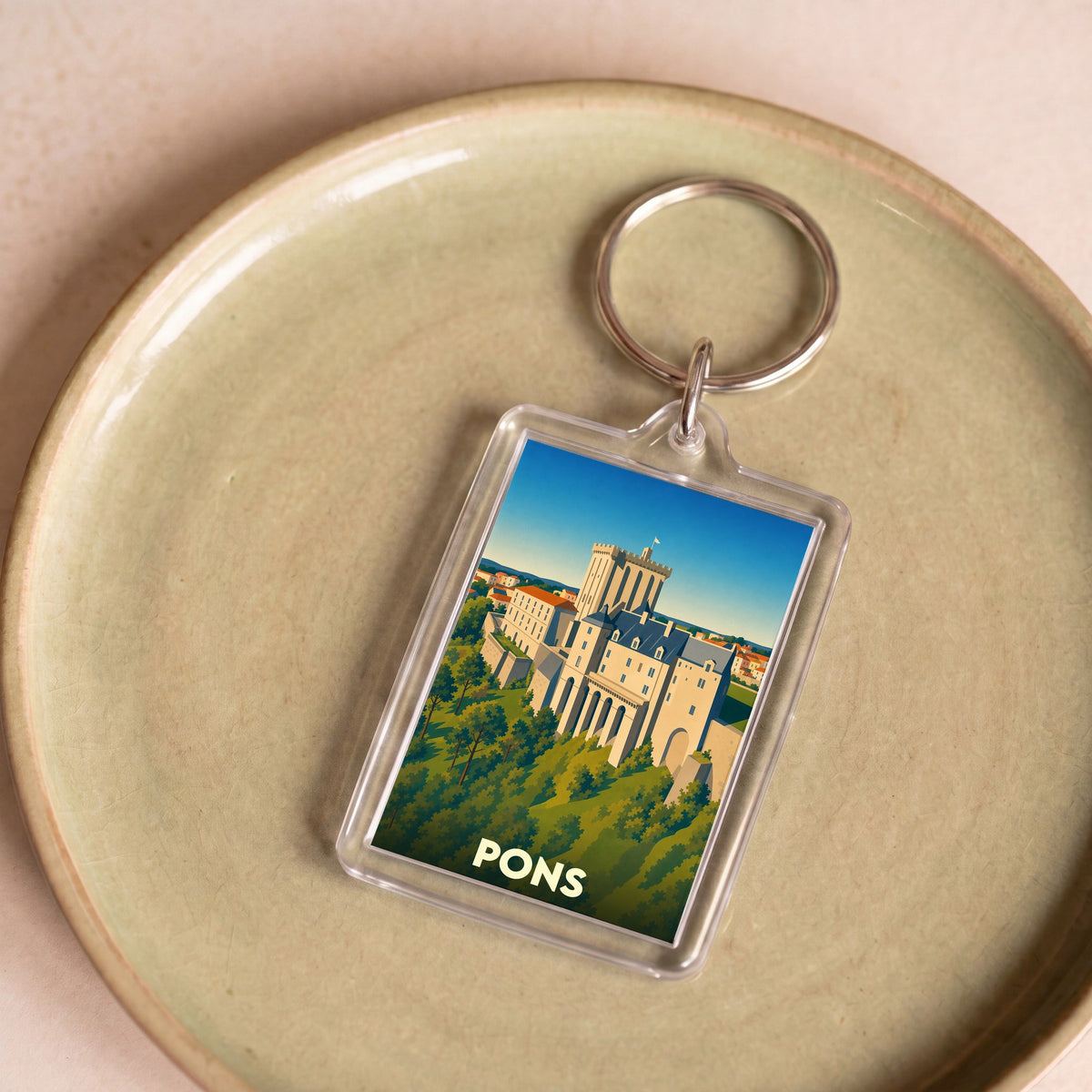 Porte-clés souvenir de la ville de Pons avec une illustration stylisée de son donjon médiéval.