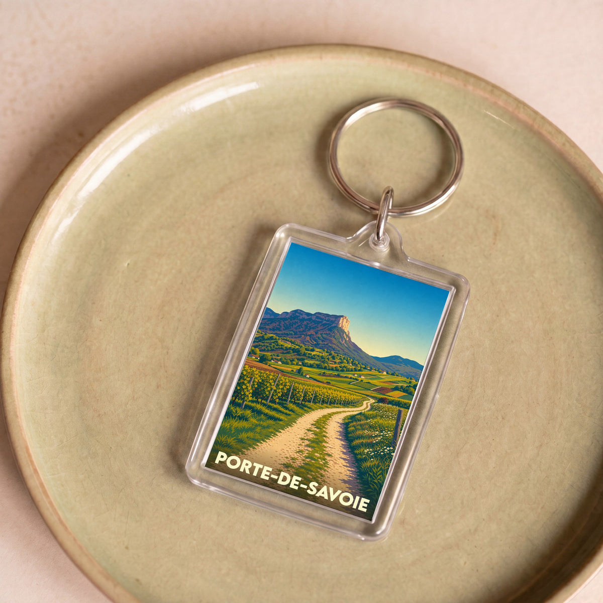 Porte-clés souvenir de la ville de Porte-de-Savoie avec une illustration stylisée de paysages vallonnés.