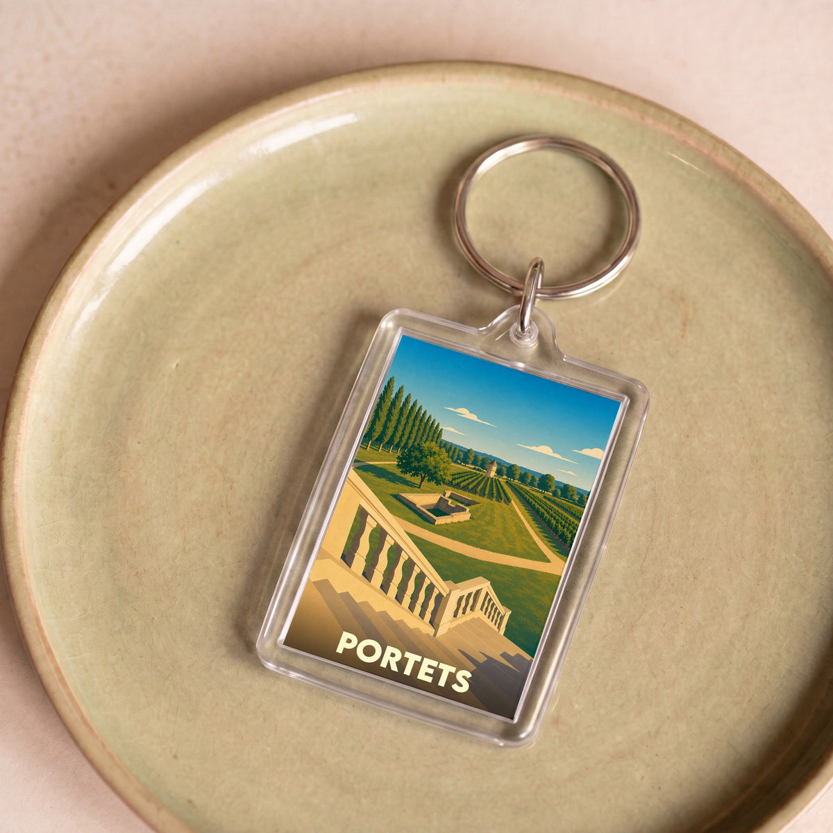 Porte-clés souvenir de la ville de Portets avec une illustration stylisée de son paysage.