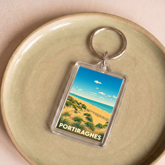 Porte-clés souvenir de la ville de Portiragnes avec une illustration stylisée de ses dunes et de la mer.