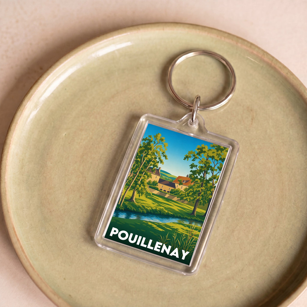 Porte-clés souvenir de la ville de Pouillenay avec une illustration paysagère stylisée.