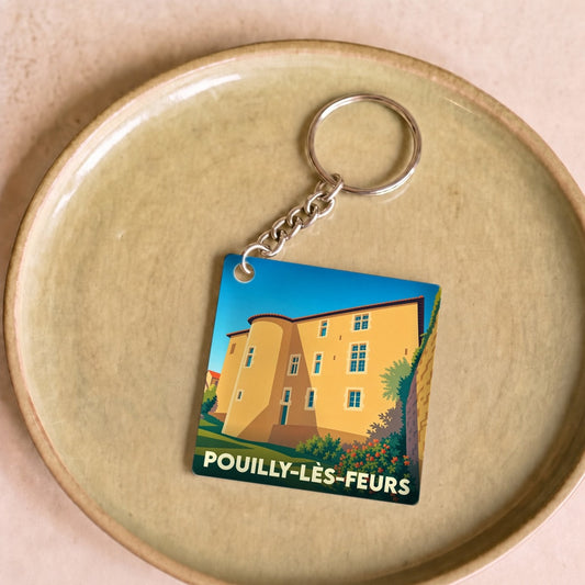 Porte-clés souvenir de la ville de Pouilly-lès-Feurs avec une illustration stylisée de son patrimoine architectural.
