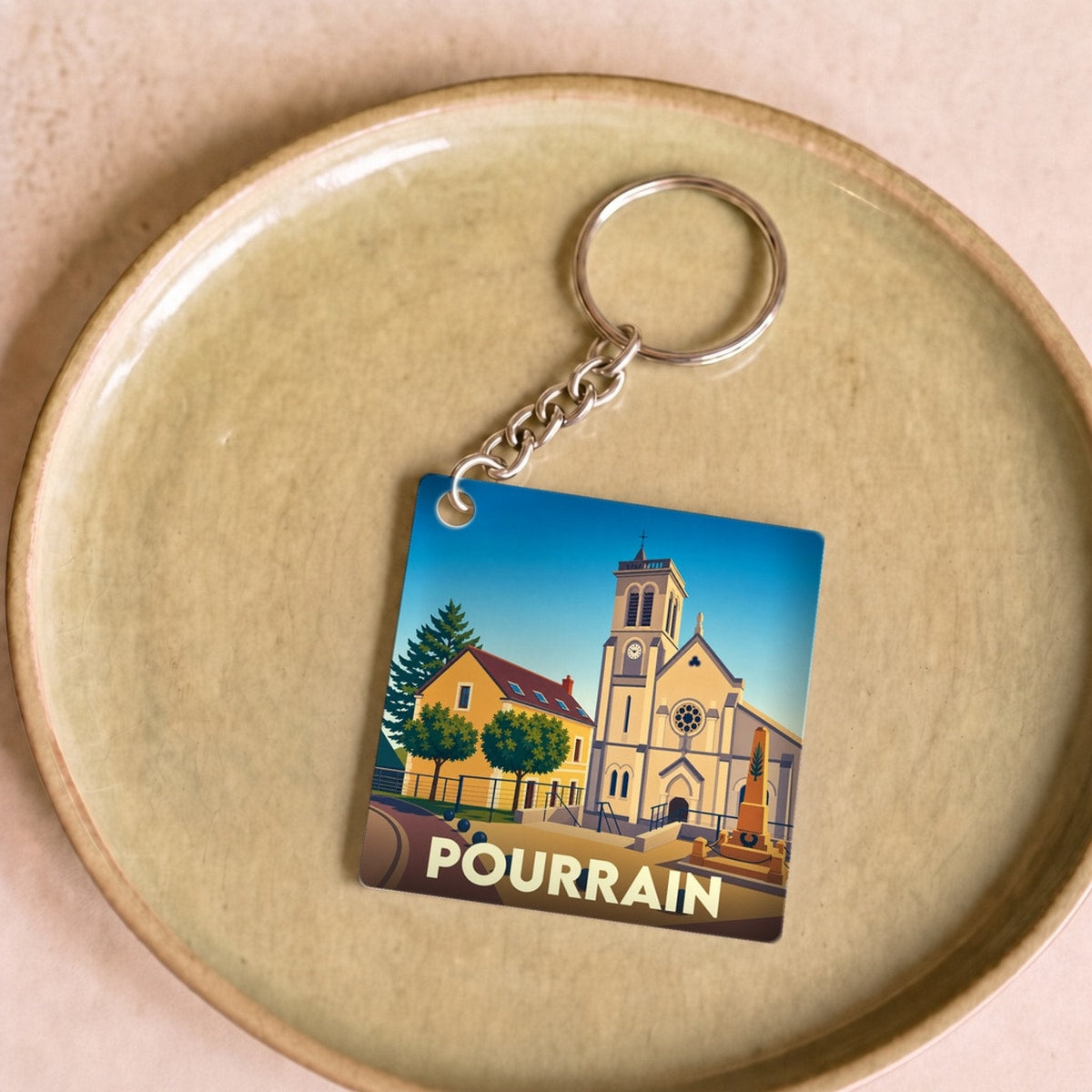 Porte-clés souvenir de la ville de Pourrain avec une illustration stylisée.