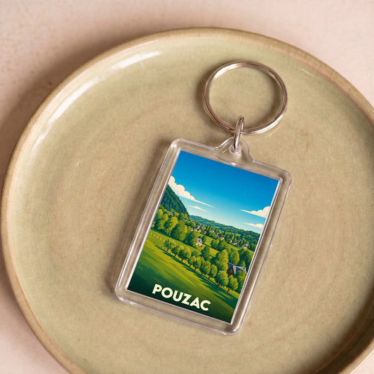 Porte-clés souvenir de la ville de Pouzac avec une illustration stylisée de son paysage vallonné.