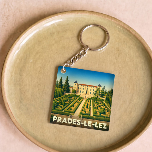Porte-clés souvenir de la ville de Prades-le-Lez avec une illustration stylisée de son château et de ses jardins.
