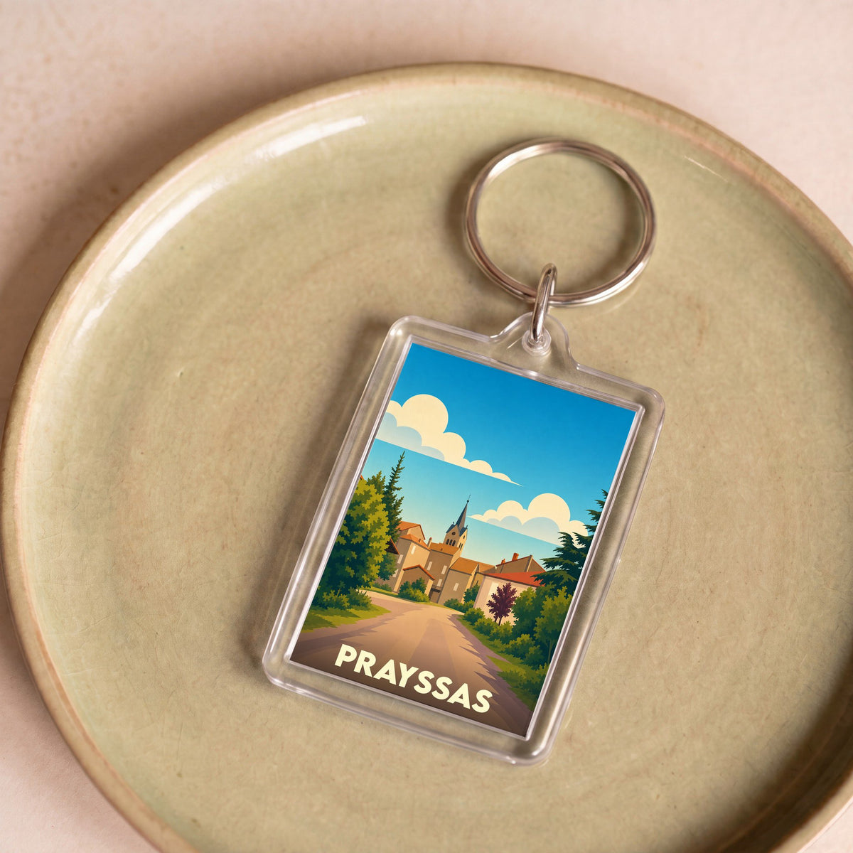 Porte-clés souvenir de la ville de Prayssas avec une illustration stylisée.