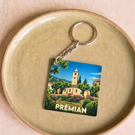 Porte-clés souvenir de la ville de Prémian avec une illustration stylisée de son église et de paysages ensoleillés.