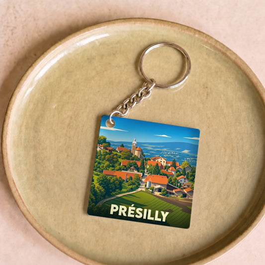Porte-clés souvenir de la ville de Présilly avec une illustration stylisée d'un village pittoresque.