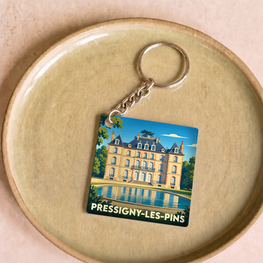 Porte-clés souvenir de Pressigny-les-Pins avec une illustration stylisée d'un château se reflétant dans l'eau.