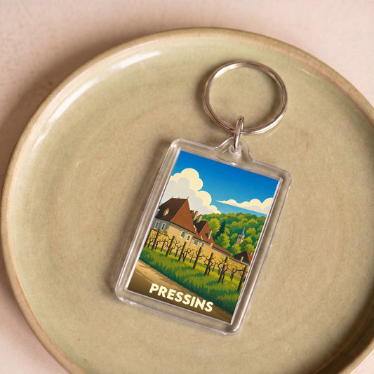 Porte-clés souvenir de la commune de Pressins avec une illustration stylisée de son paysage et de ses habitations.