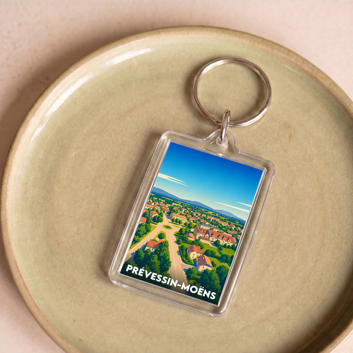 Porte-clés souvenir de la ville de Prévessin-Moëns avec une illustration stylisée.
