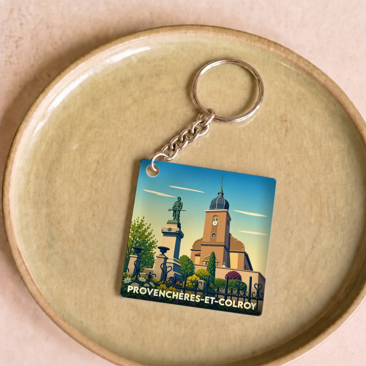 Porte-clés souvenir de la ville de Provenchères-et-Colroy avec une illustration stylisée de son église et d'un monument.