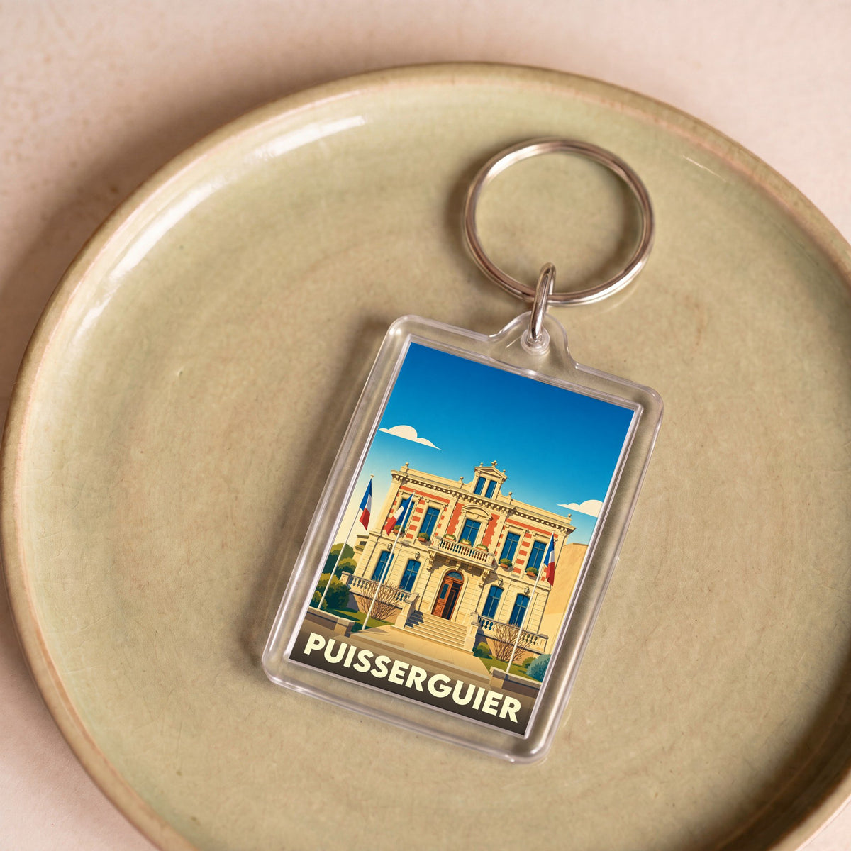 Porte-clés souvenir de la ville de Puisserguier avec une illustration stylisée de sa mairie.