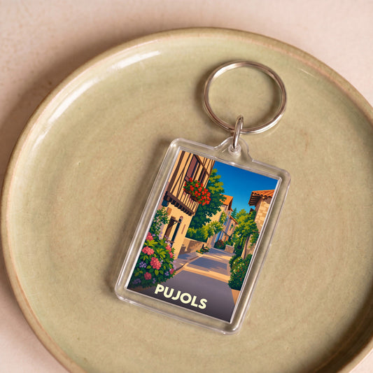 Porte-clés souvenir de la ville de Pujols avec une illustration stylisée d'une ruelle fleurie.