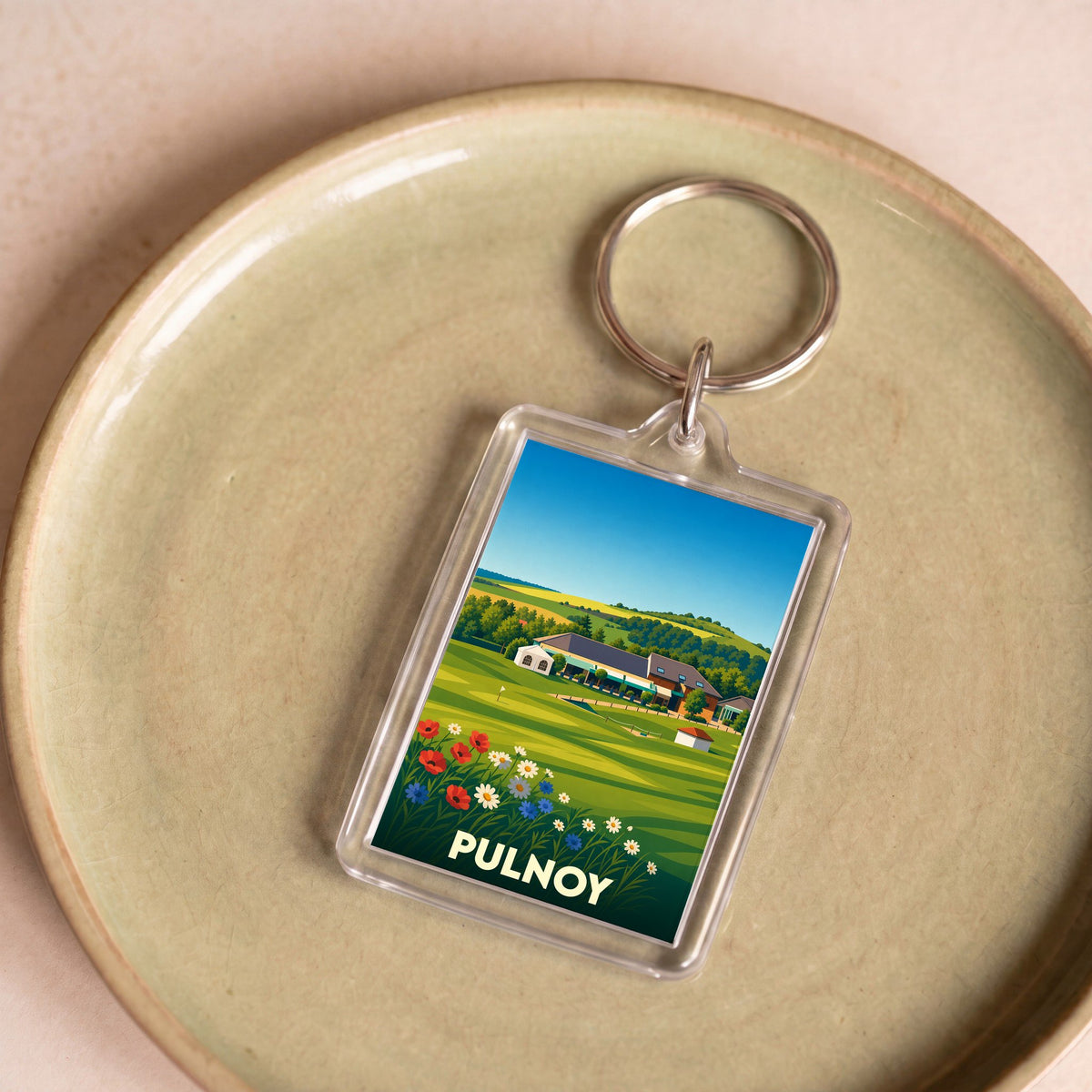 Porte-clés souvenir de la ville de Pulnoy avec une illustration stylisée de son paysage et de son golf.