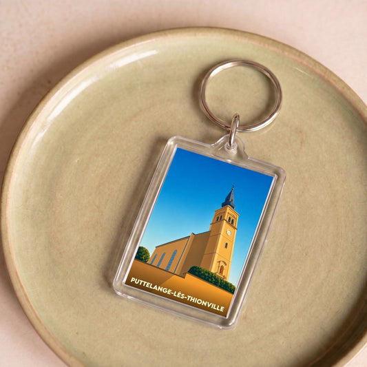Porte-clés souvenir de la ville de Puttelange-lès-Thionville avec une illustration stylisée de son église.