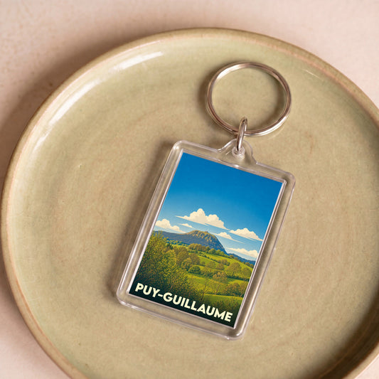 Porte-clés souvenir de la ville de Puy-Guillaume avec une illustration de paysage vallonné.
