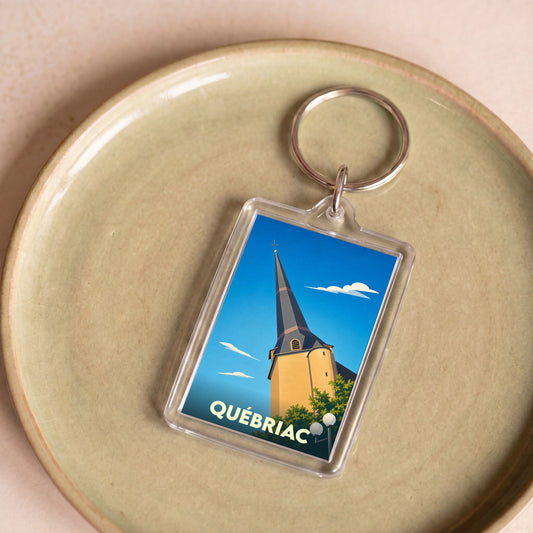 Porte-clés souvenir de la ville de Québriac avec une illustration stylisée de son église.