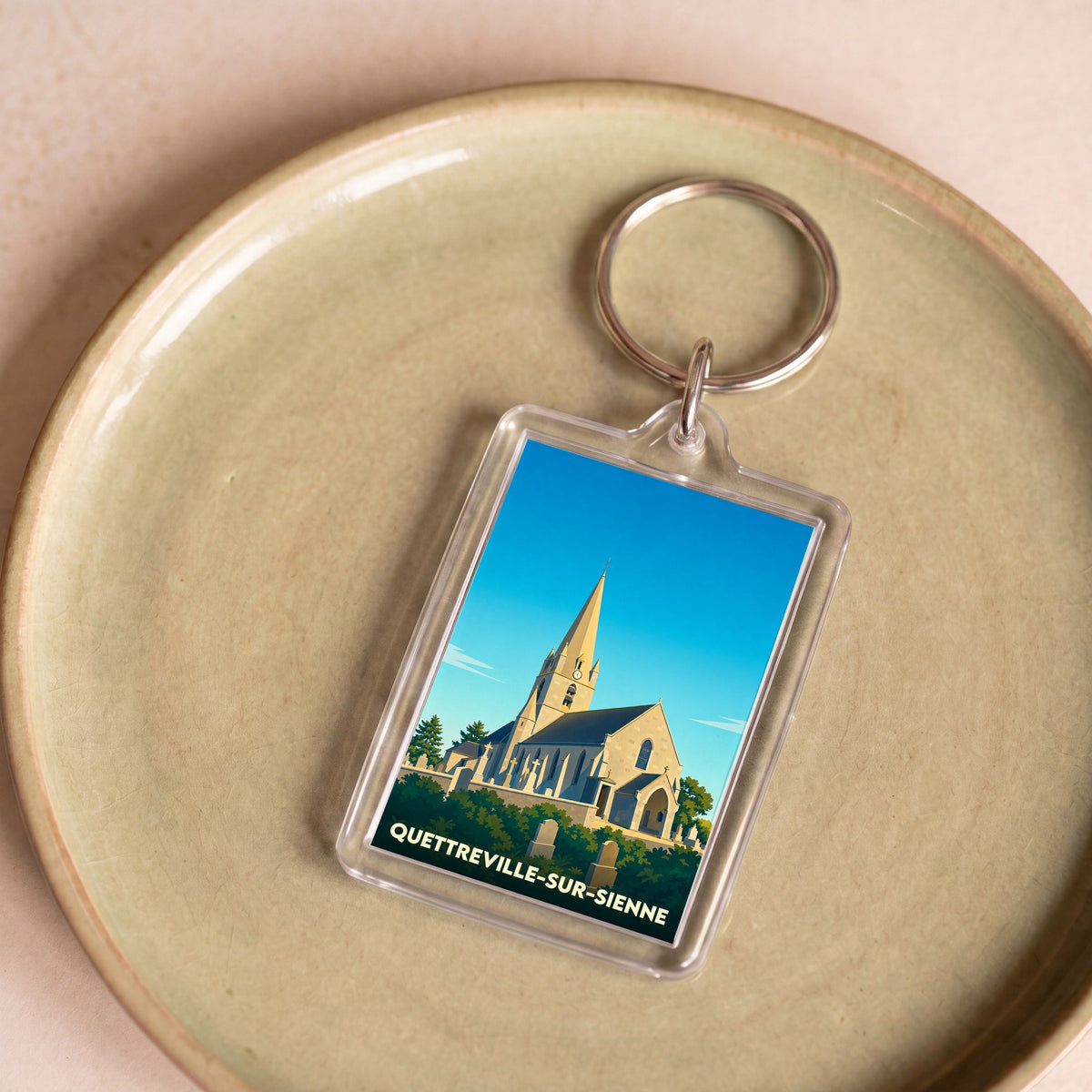 Porte-clés souvenir de la ville de Quettreville-sur-Sienne avec une illustration stylisée de son église.