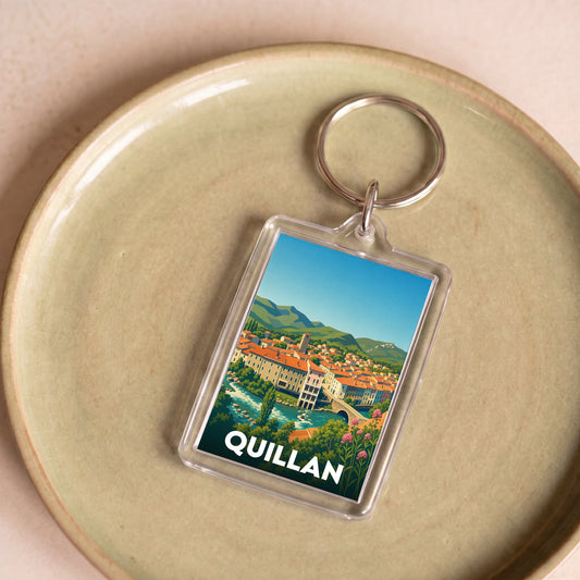 Porte-clés souvenir de la ville de Quillan avec une illustration stylisée de son paysage.