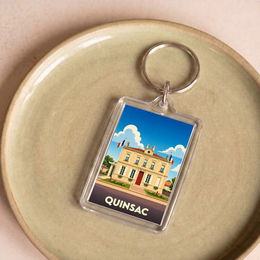 Porte-clés souvenir de la ville de Quinsac avec une illustration stylisée de sa mairie.