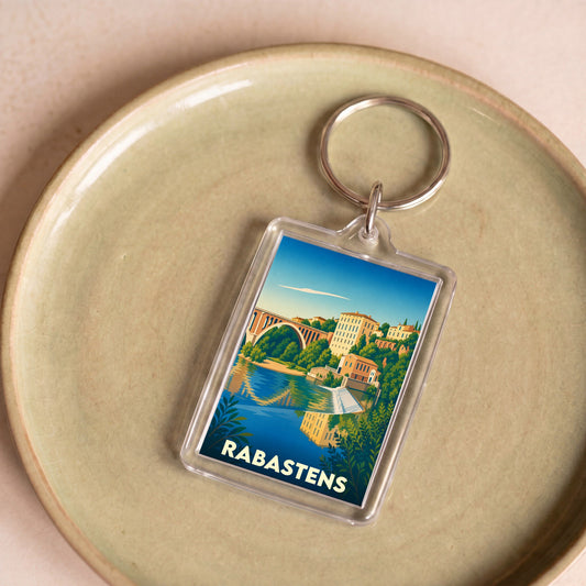 Porte-clés souvenir de la ville de Rabastens avec une illustration stylisée d'un pont et de bâtiments au bord de l'eau.