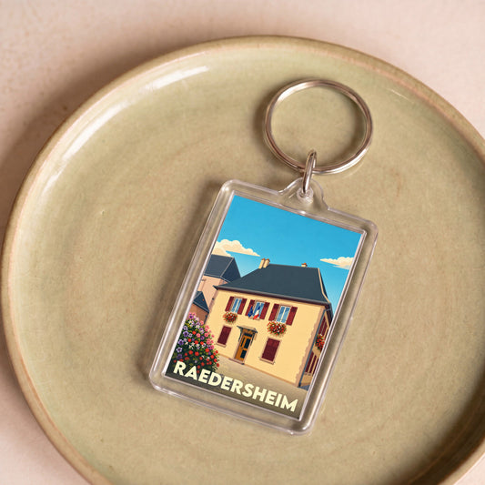 Porte-clés souvenir de la ville de Raedersheim avec une illustration stylisée de sa mairie fleurie.
