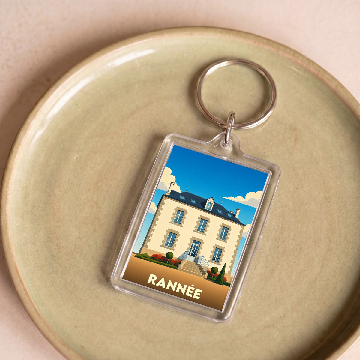 Porte-clés souvenir de la ville de Rannée avec une illustration stylisée d'une maison bourgeoise.