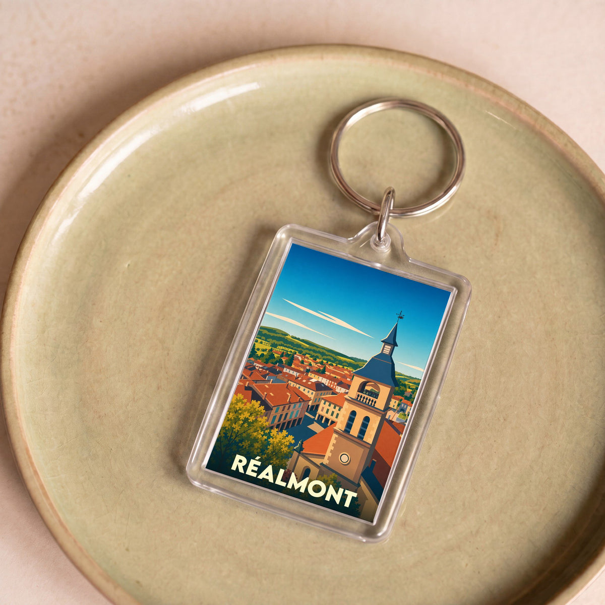 Porte-clés souvenir de la ville de Réalmont avec une illustration stylisée.