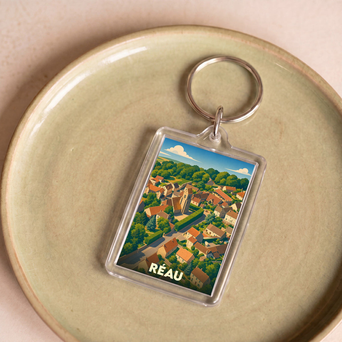 Porte-clés souvenir de la ville de Réau avec une illustration stylisée vue du ciel.