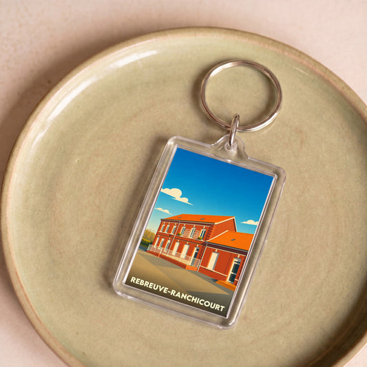 Porte-clés souvenir de la ville de Rebreuve-Ranchicourt avec une illustration stylisée.