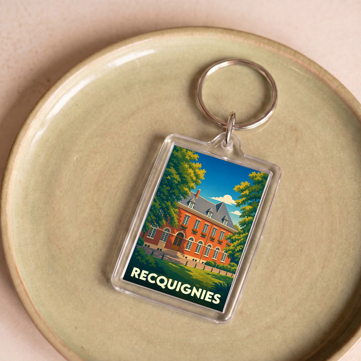 Porte-clés souvenir de la ville de Recquignies avec une illustration stylisée.