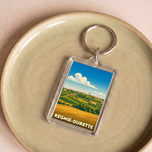 Porte-clés souvenir de la ville de Régnié-Durette avec une illustration stylisée de paysages de vignes.