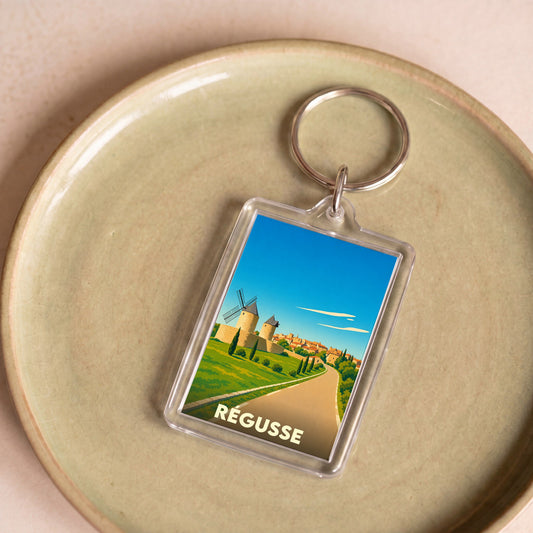Porte-clés souvenir de la ville de Régusse avec une illustration stylisée de ses moulins.