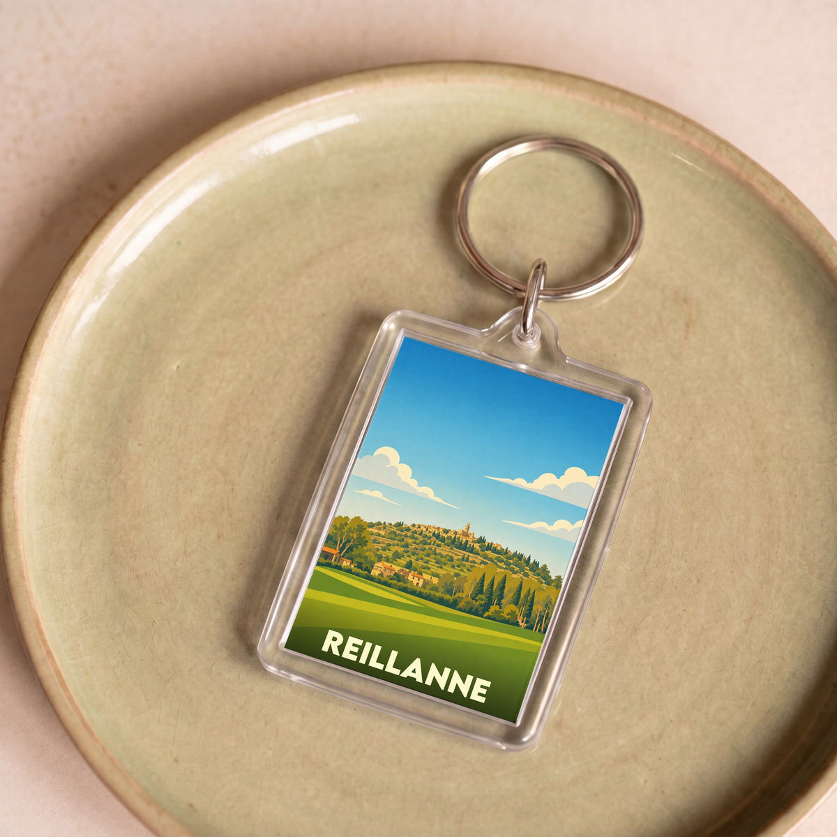 Porte-clés souvenir de la ville de Reillanne avec une illustration stylisée.
