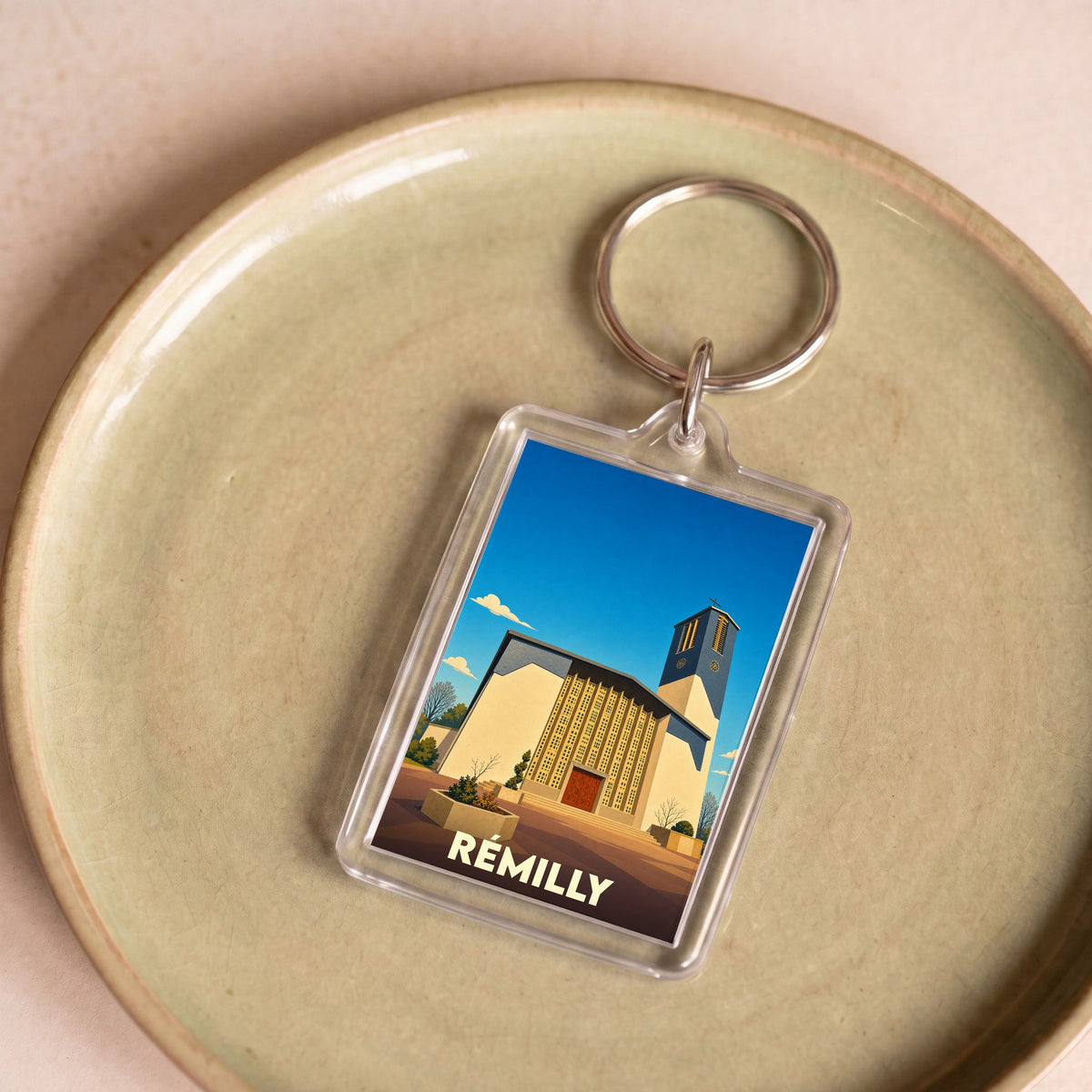 Porte-clés souvenir de la ville de Rémilly avec une illustration stylisée de son église.