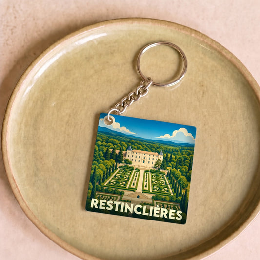 Porte-clés souvenir de la ville de Restinclières avec une illustration stylisée du domaine et de ses jardins.