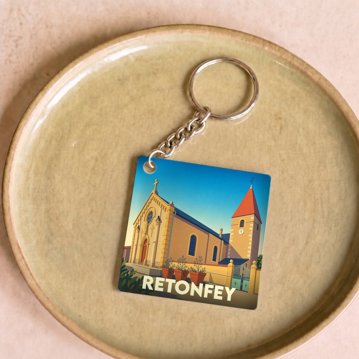 Porte-clés souvenir de la ville de Retonfey avec une illustration stylisée de son église.