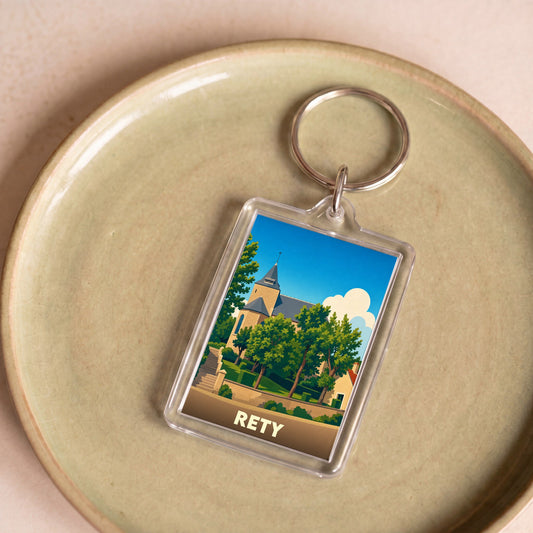 Porte-clés souvenir de la ville de Rety avec une illustration stylisée de son église entourée de verdure.