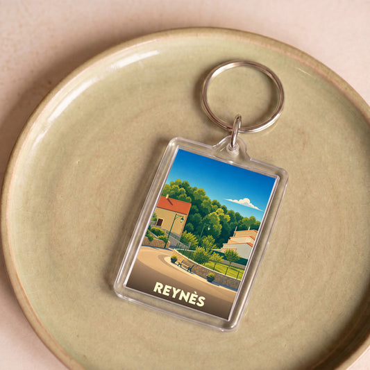 Porte-clés souvenir de la ville de Reynès avec une illustration stylisée.
