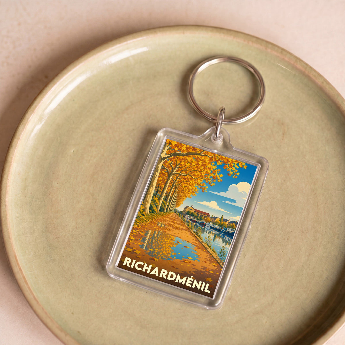 Porte-clés souvenir de la ville de Richardménil avec une illustration stylisée d'un canal en automne.